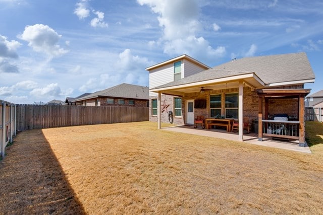 back of property featuring brick siding, a patio, a fenced backyard, a yard, and a ceiling fan