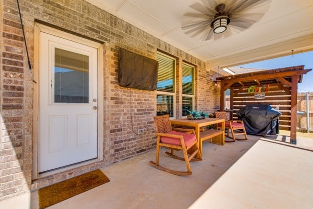 property entrance featuring brick siding, a porch, and ceiling fan