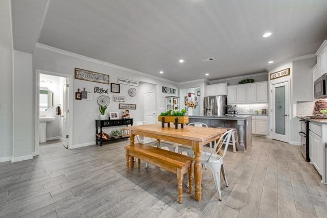 dining room featuring light wood-style flooring, recessed lighting, baseboards, and ornamental molding