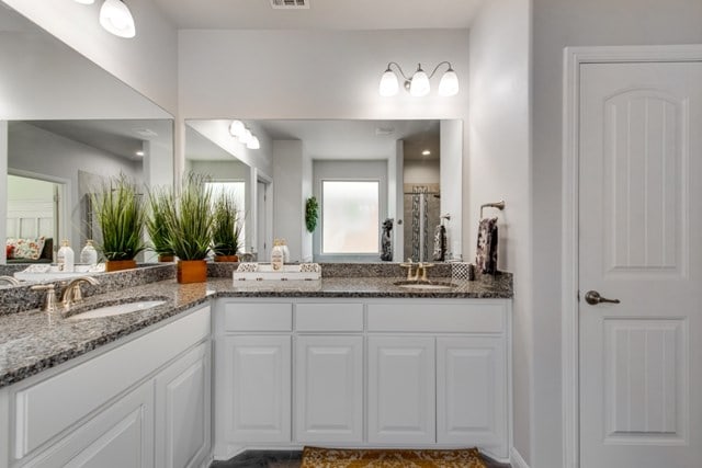 full bath with a sink, visible vents, and double vanity