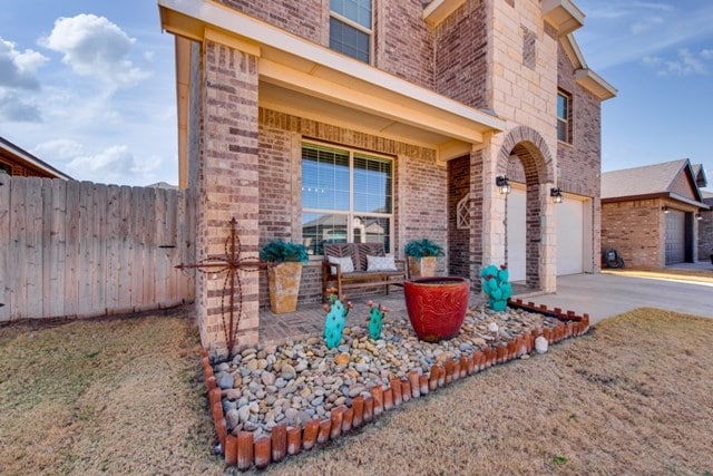 view of front of home with brick siding, concrete driveway, and fence