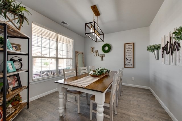 dining space with wood finished floors, visible vents, and baseboards