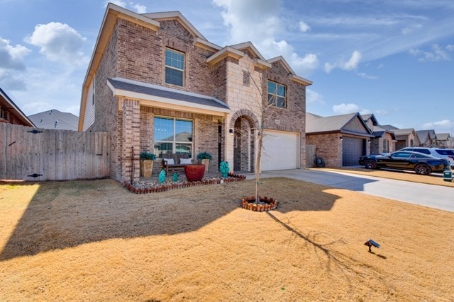 traditional-style home with a garage, brick siding, driveway, and fence