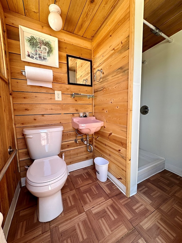 bathroom featuring parquet flooring, sink, wooden ceiling, toilet, and wood walls