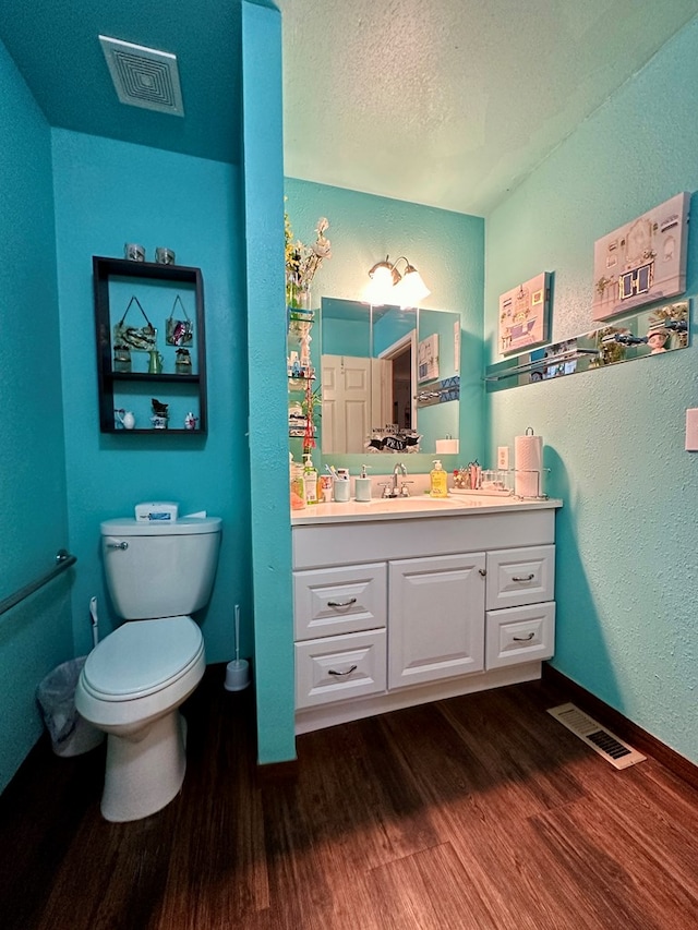 bathroom with vanity, wood-type flooring, a textured ceiling, and toilet