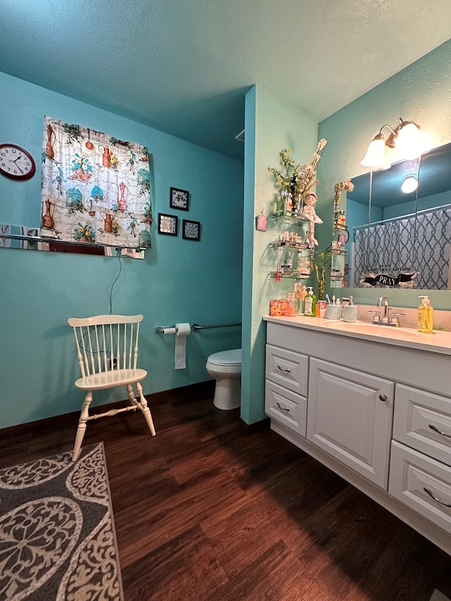 bathroom featuring vanity, toilet, wood-type flooring, and a textured ceiling