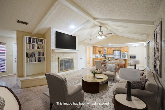 living room featuring a textured ceiling, ceiling fan, a fireplace, vaulted ceiling with beams, and light tile patterned flooring