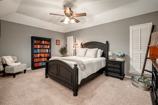bedroom with baseboards, a ceiling fan, a tray ceiling, and light colored carpet