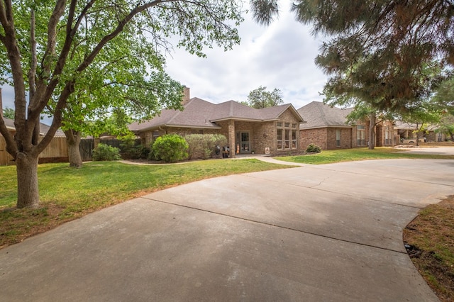 view of front of house with fence, a chimney, a front lawn, and brick siding