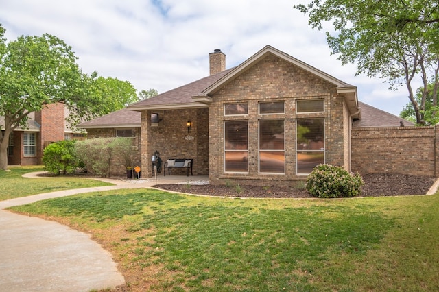 back of house with a patio, a yard, and brick siding