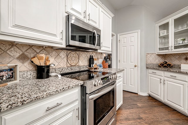kitchen featuring glass insert cabinets, white cabinets, light stone counters, dark wood finished floors, and stainless steel appliances