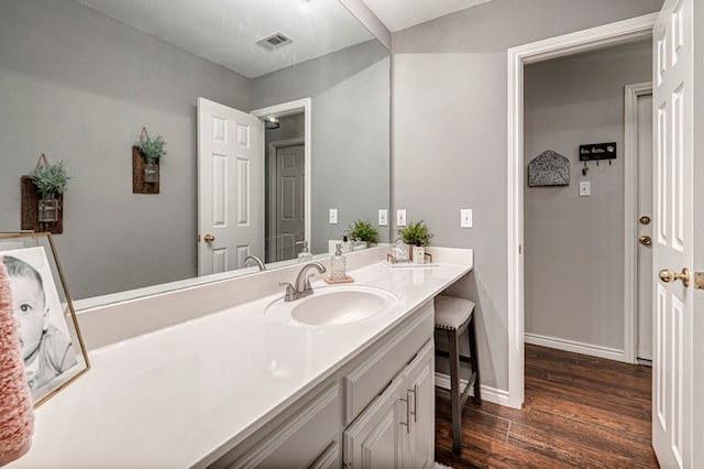bathroom featuring baseboards, visible vents, wood finished floors, and vanity