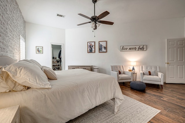 bedroom featuring ceiling fan, visible vents, dark wood-style floors, and a walk in closet
