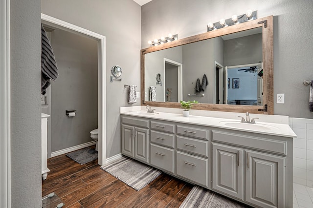 bathroom featuring a sink, double vanity, toilet, and wood finished floors