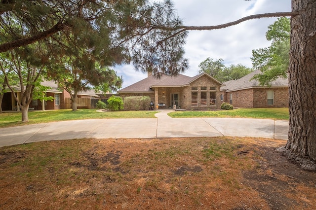 view of front of home with brick siding, fence, and a front yard