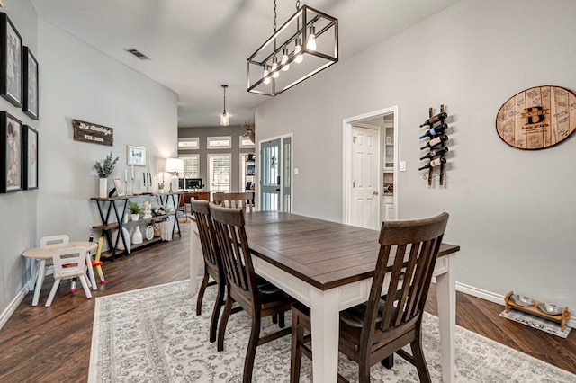 dining area with a chandelier, baseboards, visible vents, and dark wood-type flooring