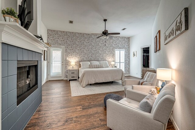 bedroom featuring visible vents, ceiling fan, wood finished floors, and a tile fireplace