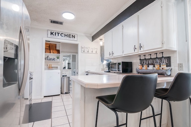 kitchen with white cabinetry, appliances with stainless steel finishes, visible vents, ornamental molding, and a peninsula