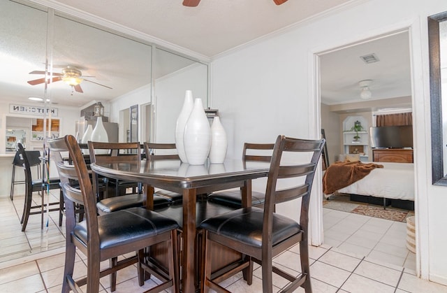dining area featuring light tile patterned floors, ceiling fan, ornamental molding, and visible vents