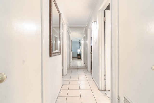 hallway with light tile patterned floors, crown molding, and baseboards