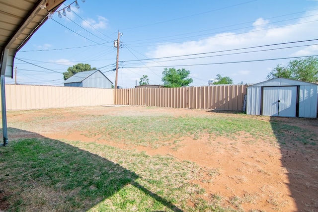 view of yard featuring fence, a shed, and an outbuilding