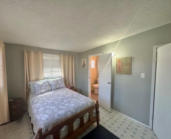 bedroom with connected bathroom and a textured ceiling