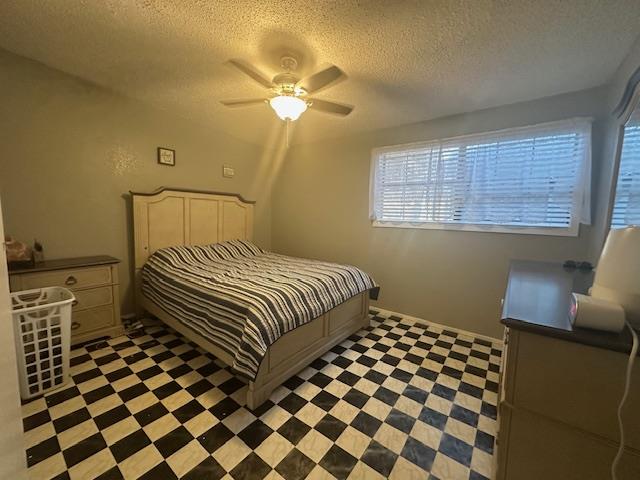 bedroom with ceiling fan and a textured ceiling