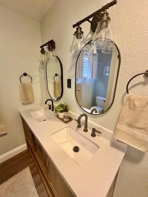 bathroom featuring toilet, hardwood / wood-style flooring, and vanity