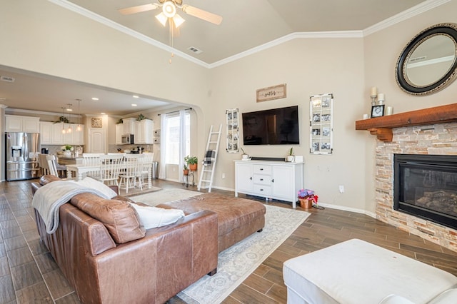 living room with ornamental molding, vaulted ceiling, ceiling fan, dark wood-type flooring, and a fireplace