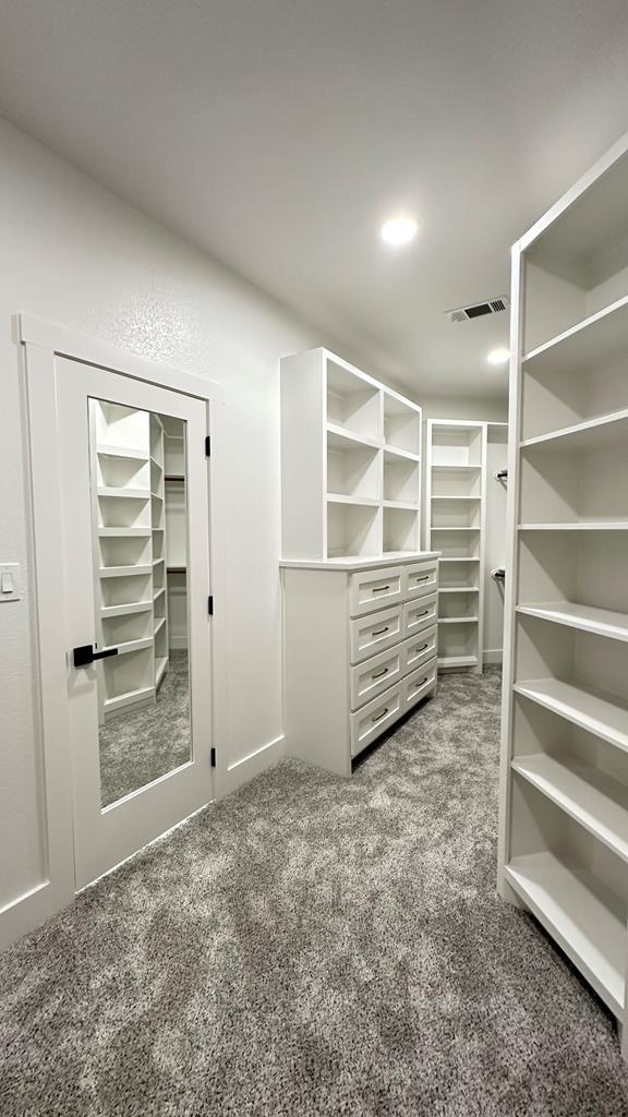 walk in closet featuring dark colored carpet