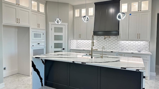 kitchen featuring white cabinetry, hanging light fixtures, white appliances, and a kitchen island with sink