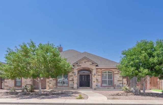 7604 Keyhaven, Odessa, TX 79765 - view of front facade with stone siding, brick siding, a chimney, and a shingled roof