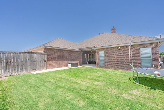 7604 Keyhaven, Odessa, TX 79765 - back of house featuring a trampoline, brick siding, a fenced backyard, and a chimney