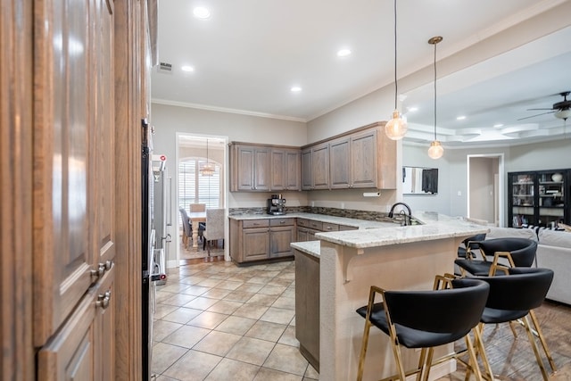 7604 Keyhaven, Odessa, TX 79765 - kitchen featuring a peninsula, a breakfast bar, crown molding, open floor plan, and light stone countertops