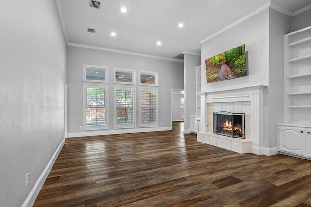 unfurnished living room with built in shelves, dark hardwood / wood-style flooring, a tiled fireplace, and crown molding