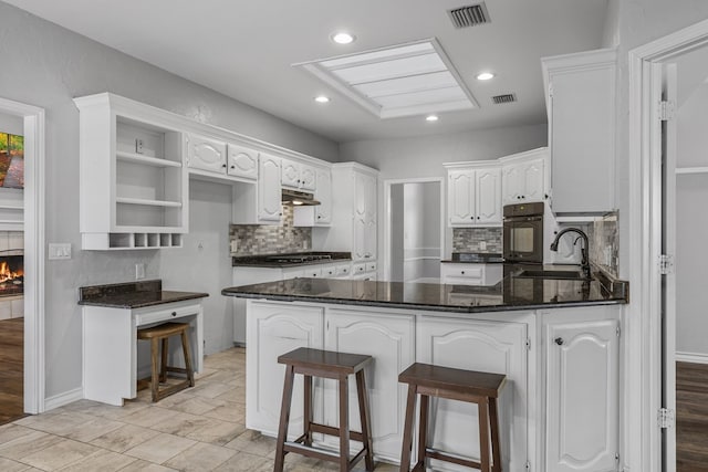 kitchen with a breakfast bar, sink, white cabinets, decorative backsplash, and kitchen peninsula