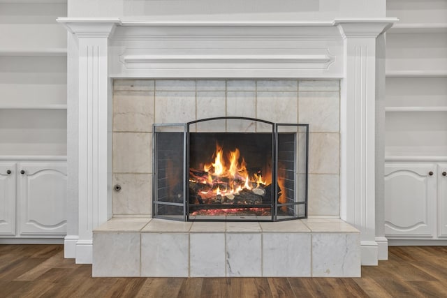 interior details with a tiled fireplace and hardwood / wood-style flooring