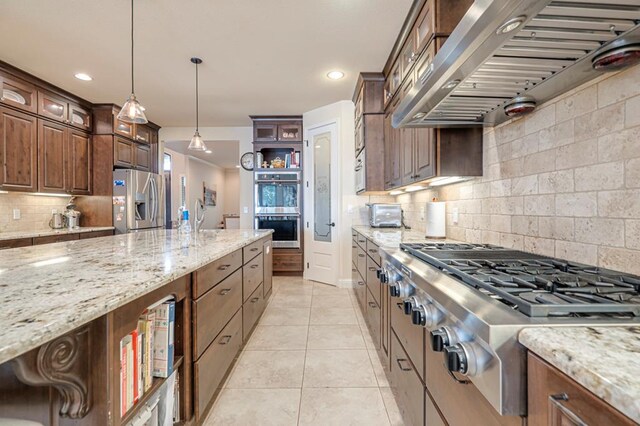 kitchen featuring wall chimney exhaust hood, glass insert cabinets, a sink, and a kitchen island with sink