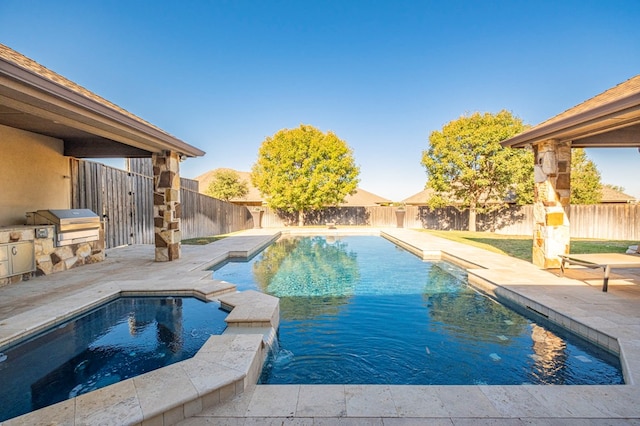 view of swimming pool with an outdoor kitchen, a patio, and grilling area