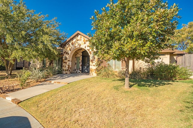 view of front of home with stone siding, a front yard, and stucco siding