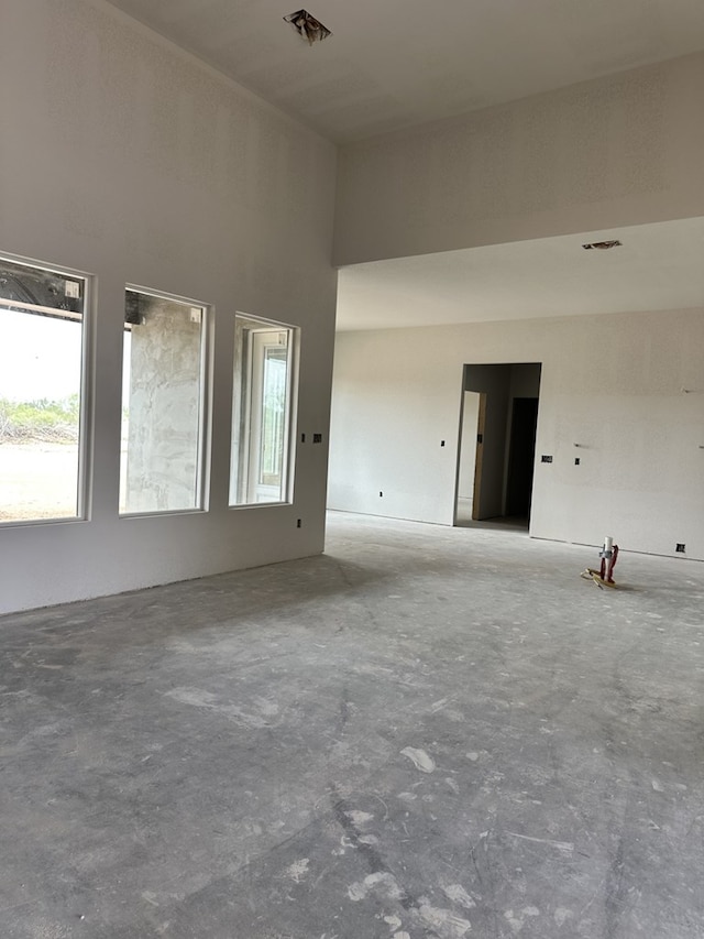 empty room featuring concrete flooring and a towering ceiling
