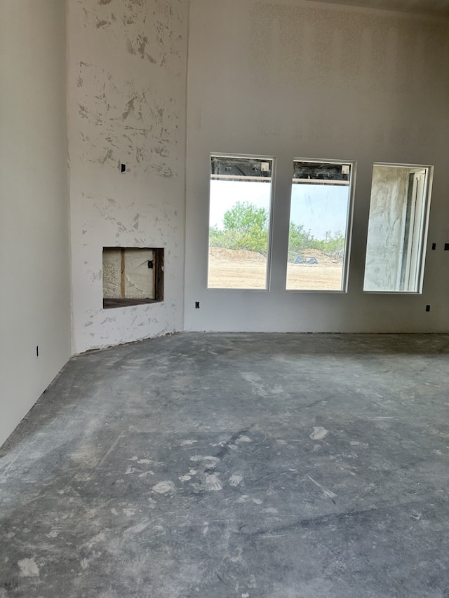 unfurnished living room with a fireplace and concrete floors