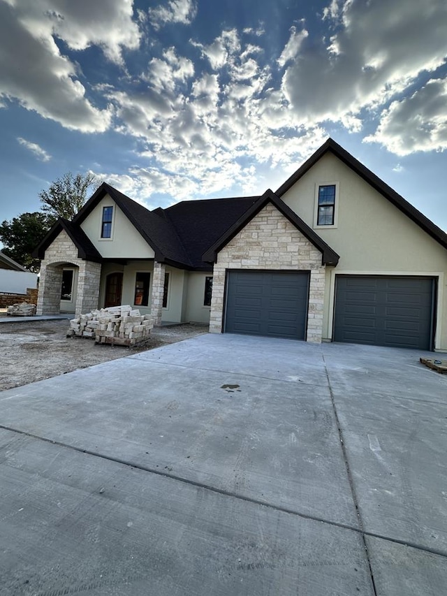 view of front of property with stone siding, concrete driveway, stucco siding, and a garage
