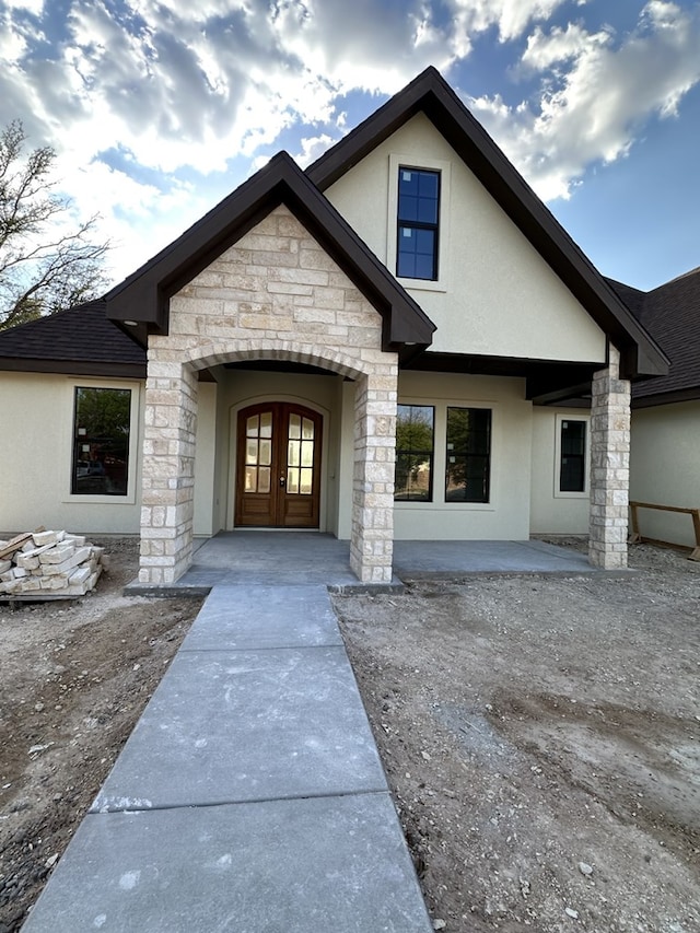 view of exterior entry featuring french doors, stucco siding, and stone siding