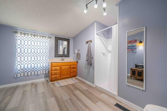 50031 E County Rd 71, Midland, TX 79705 - full bath featuring a textured ceiling, wood finished floors, vanity, a shower with shower curtain, and toilet