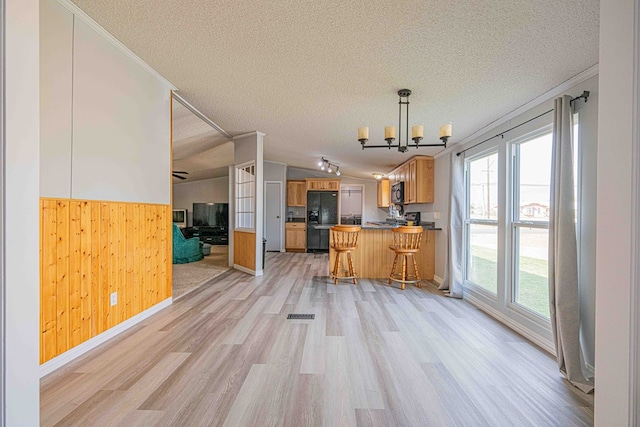 50031 E County Rd 71, Midland, TX 79705 - kitchen featuring black appliances, a textured ceiling, brown cabinets, light wood finished floors, and open floor plan
