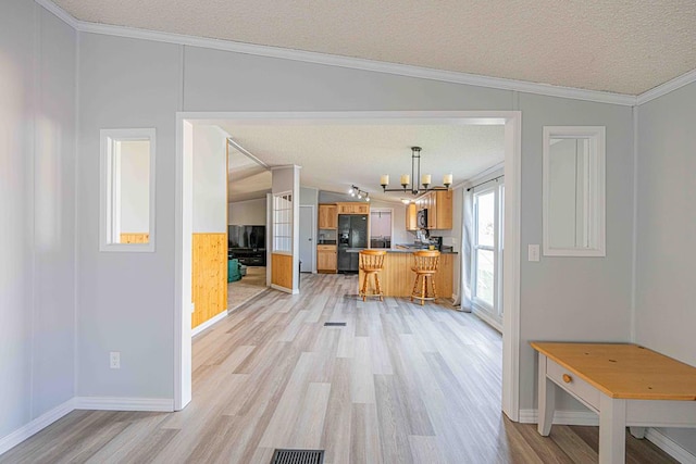 50031 E County Rd 71, Midland, TX 79705 - kitchen featuring black fridge, brown cabinetry, a chandelier, light wood-type flooring, and a textured ceiling