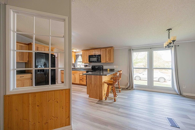 50031 E County Rd 71, Midland, TX 79705 - kitchen featuring black appliances, light wood-style floors, a textured ceiling, a kitchen bar, and dark countertops