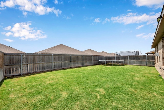 view of yard with a trampoline and a fenced backyard
