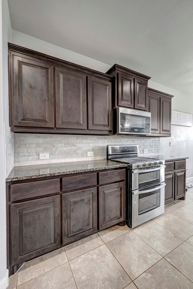 kitchen featuring light tile patterned floors, dark brown cabinetry, light stone counters, stainless steel appliances, and backsplash